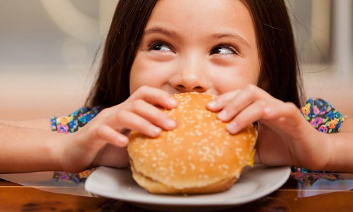 Girl eating hamburger and smiling