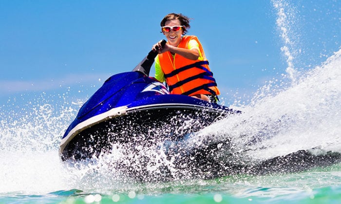 teenager on jet ski smiling while splashing water